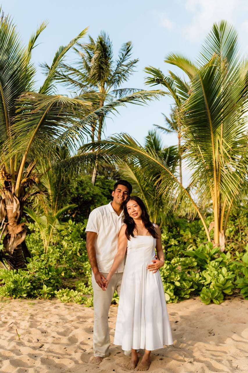 Amy and Roshan standing together beneath palms in Kauai