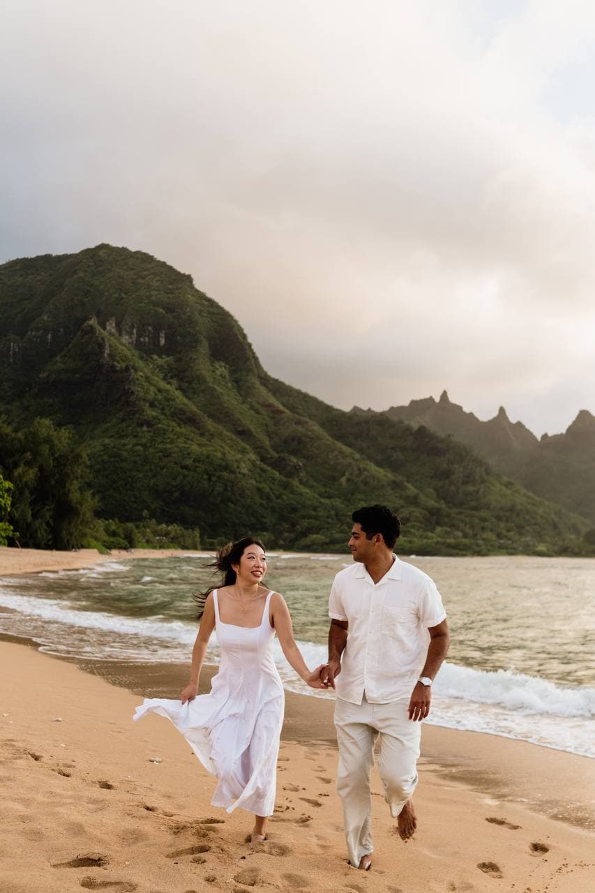 Amy and Roshan walking hand in hand on a Kauai beach