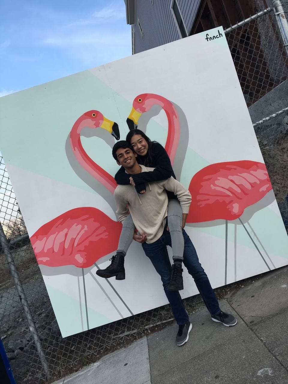 Amy and Roshan in front of a flamingo mural