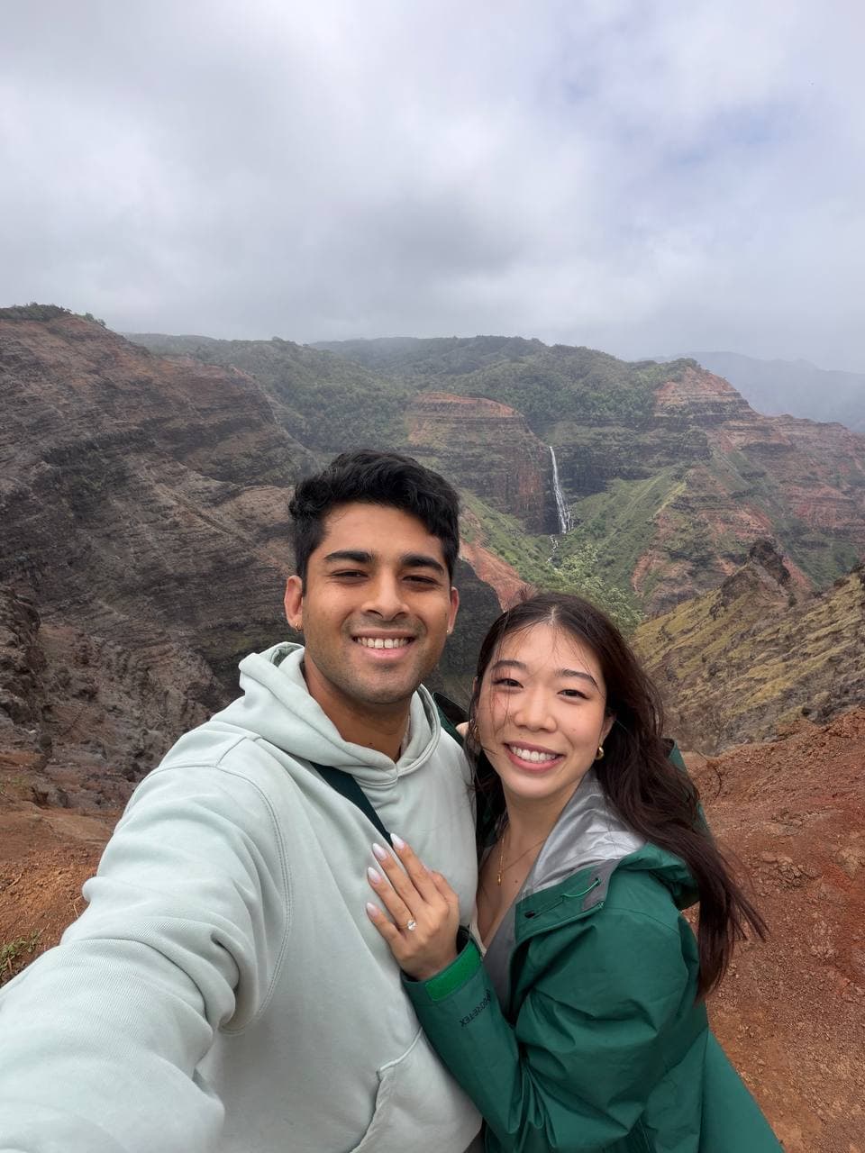 Amy and Roshan smiling together at Waimea Canyon, Kauai, with Amy's engagement ring visible
