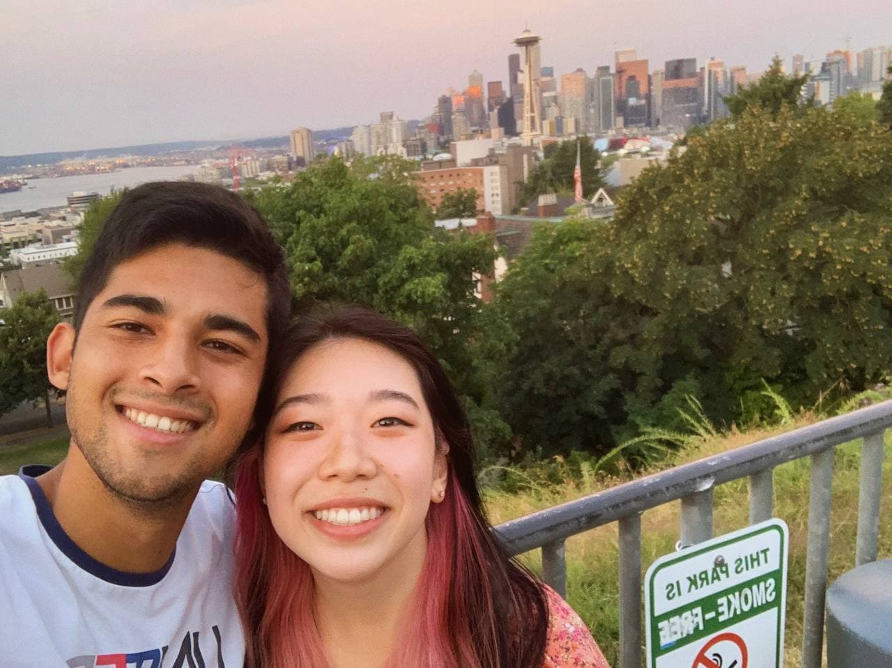 Amy and Roshan smiling with the Seattle skyline behind them